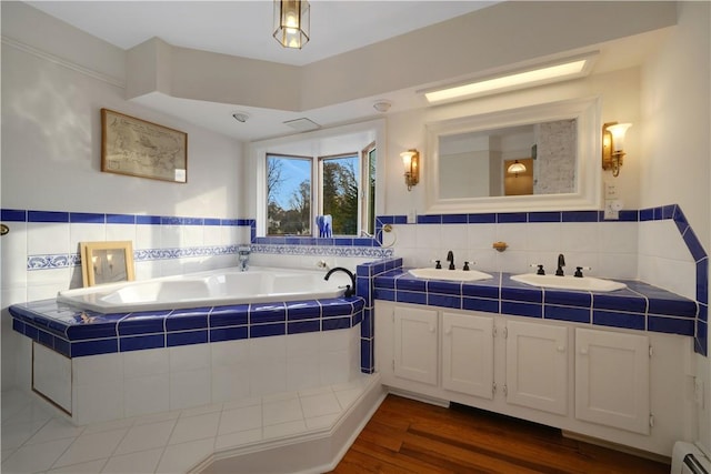 bathroom featuring vanity, a baseboard radiator, hardwood / wood-style floors, and tiled tub