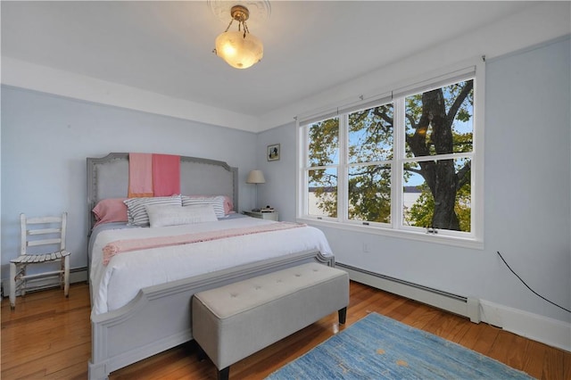 bedroom featuring baseboard heating and wood-type flooring