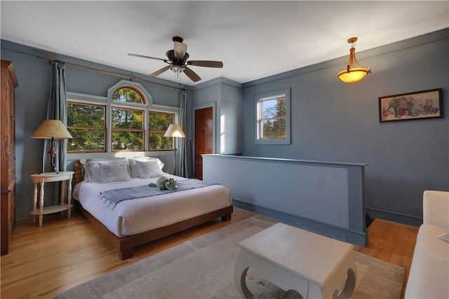 bedroom with ceiling fan, light wood-type flooring, and crown molding