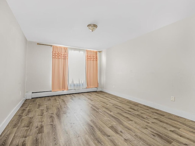 empty room with light hardwood / wood-style flooring and a baseboard radiator