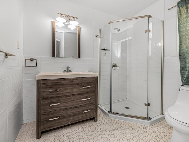 bathroom with vanity, tile walls, tile patterned flooring, toilet, and a shower with shower door