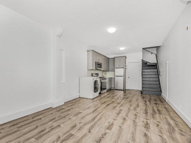 unfurnished living room featuring washer / dryer and light hardwood / wood-style floors