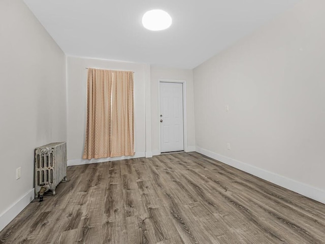 unfurnished room with wood-type flooring and radiator heating unit