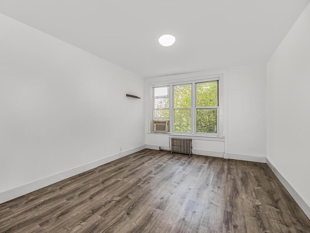 unfurnished room with dark hardwood / wood-style floors, cooling unit, and radiator