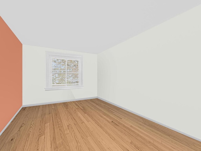 spare room featuring light wood-type flooring and vaulted ceiling