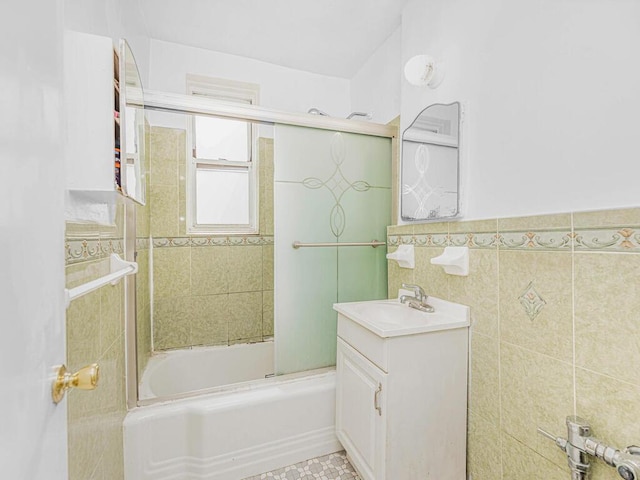 bathroom with vanity, bath / shower combo with glass door, and tile walls