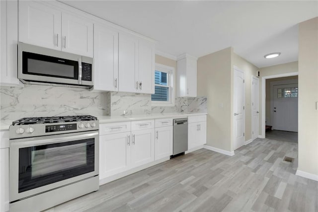 kitchen featuring white cabinets, light hardwood / wood-style floors, stainless steel appliances, and tasteful backsplash