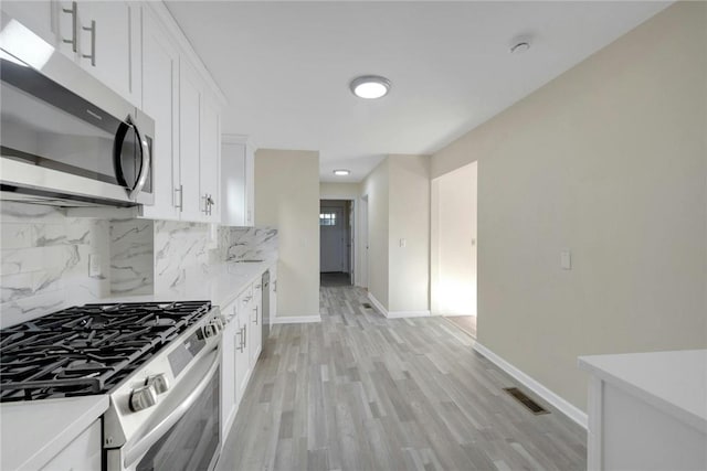 kitchen with decorative backsplash, appliances with stainless steel finishes, light hardwood / wood-style floors, and white cabinetry