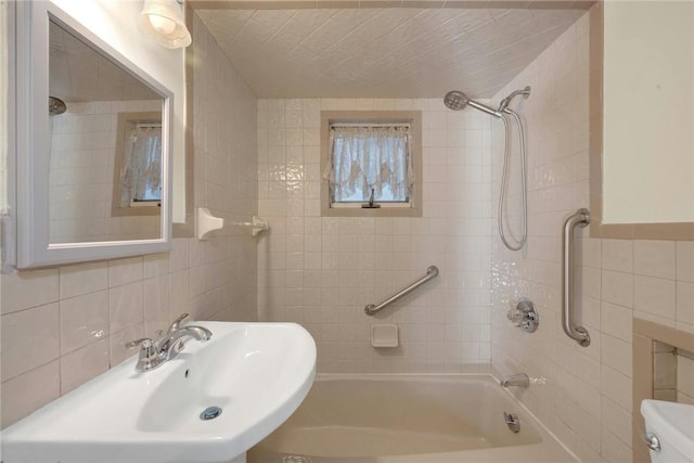 full bathroom featuring sink, tiled shower / bath combo, tasteful backsplash, toilet, and tile walls