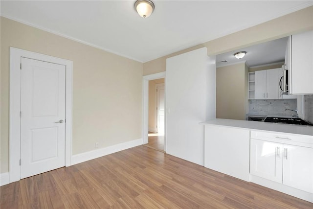 kitchen with white cabinets, decorative backsplash, sink, and light hardwood / wood-style flooring