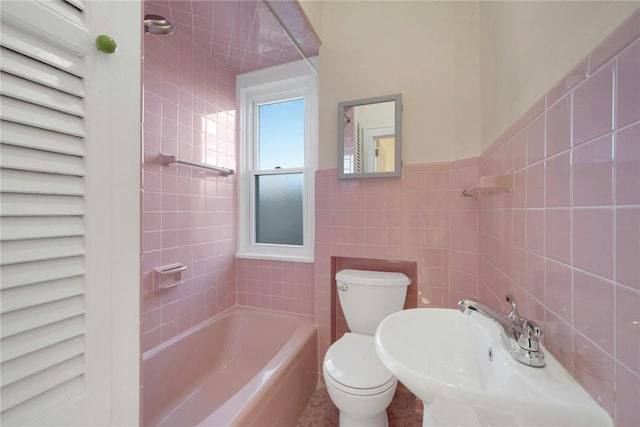 bathroom with toilet, tile walls, and tiled shower / bath