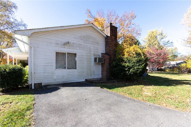 view of property exterior with a wall unit AC and a yard