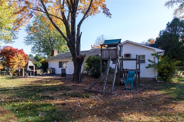 back of house with a yard and a playground