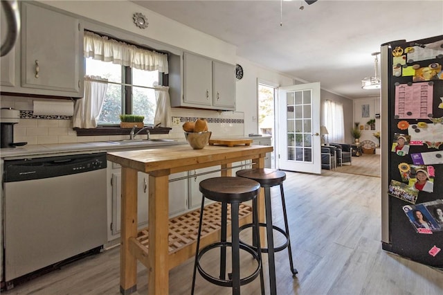 kitchen with wooden counters, french doors, appliances with stainless steel finishes, tasteful backsplash, and light hardwood / wood-style floors