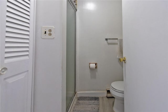 bathroom with toilet and a shower with shower door