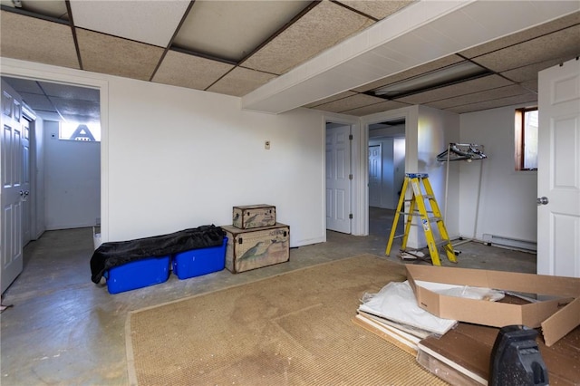 basement featuring a drop ceiling and a baseboard heating unit