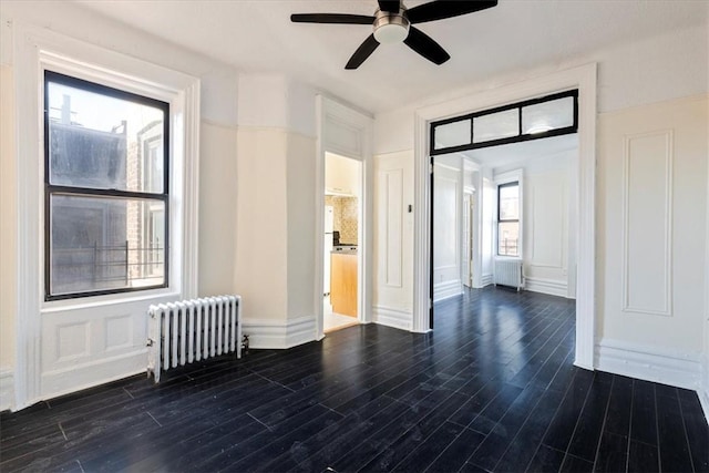 unfurnished room with a wealth of natural light, radiator, and dark wood-type flooring