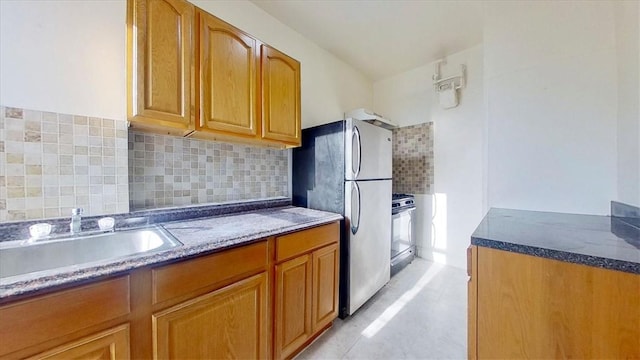 kitchen featuring dark stone countertops, decorative backsplash, sink, and appliances with stainless steel finishes