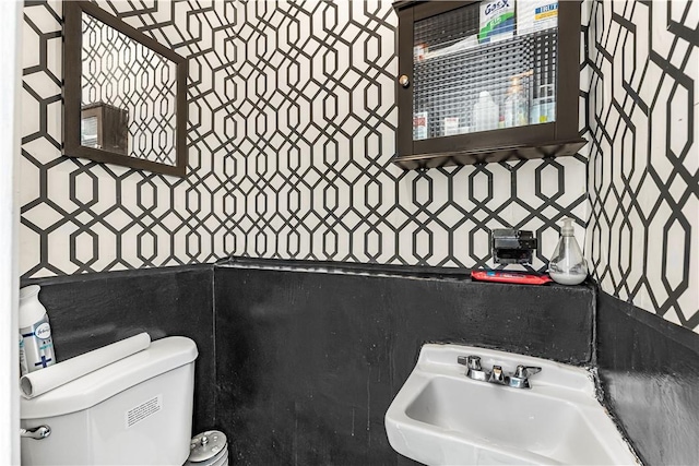 bathroom with toilet, sink, and tile walls