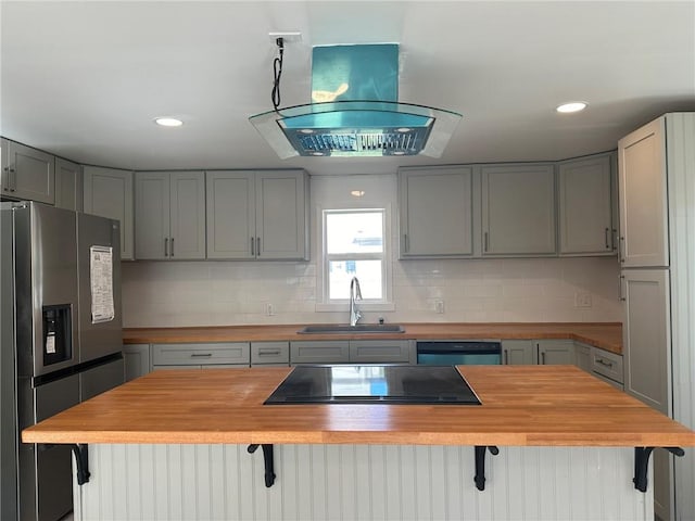 kitchen featuring stainless steel refrigerator with ice dispenser, a kitchen breakfast bar, gray cabinetry, sink, and butcher block counters