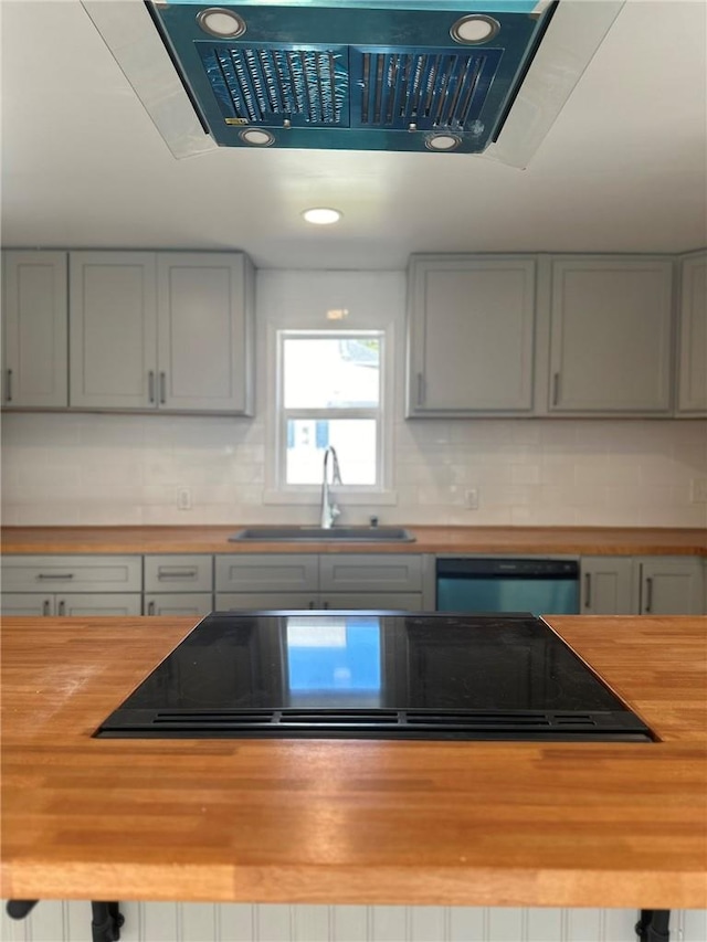 kitchen with gray cabinetry, butcher block countertops, stainless steel dishwasher, and sink