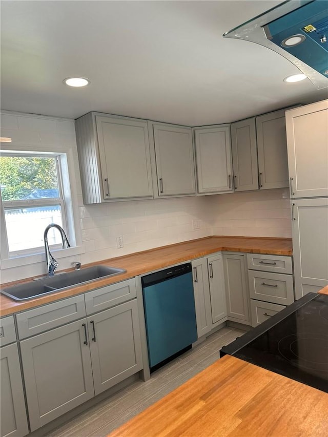 kitchen featuring gray cabinetry, dishwasher, sink, light hardwood / wood-style flooring, and butcher block countertops