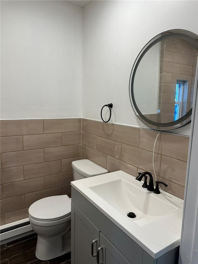 bathroom with wood-type flooring, vanity, toilet, and tile walls