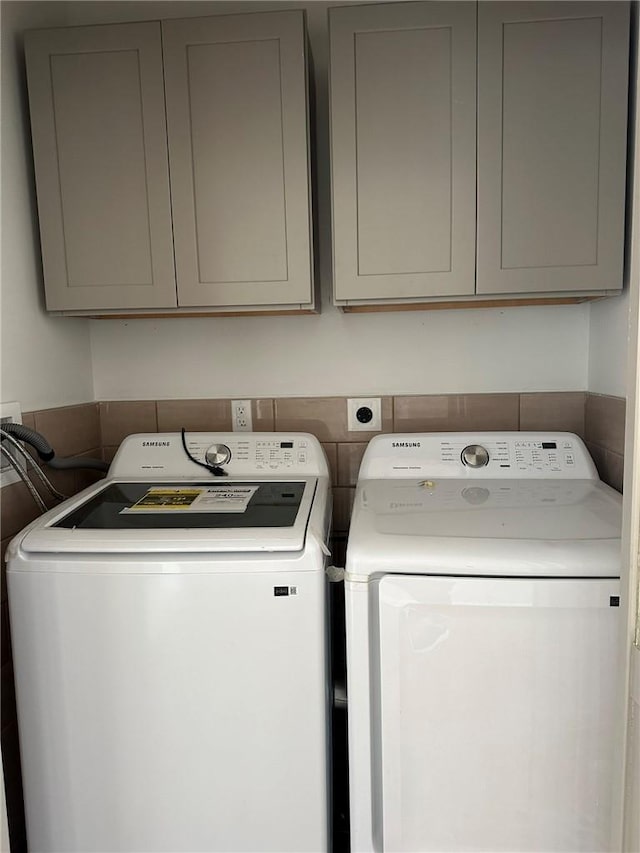 clothes washing area with cabinets and washing machine and clothes dryer