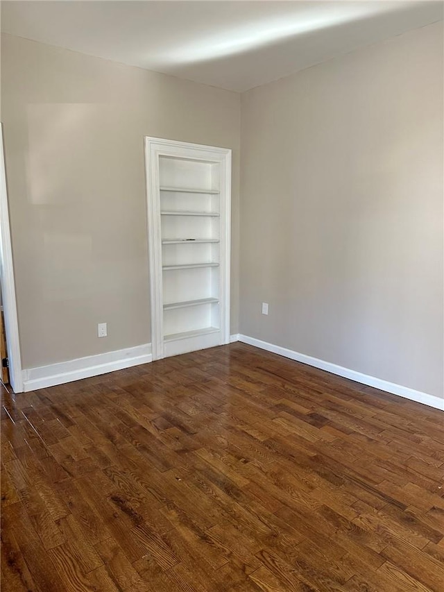 unfurnished room featuring dark wood-type flooring and built in features