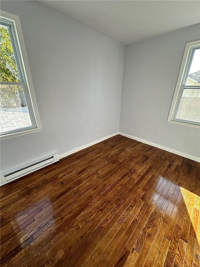 unfurnished room with plenty of natural light, a baseboard radiator, and wood-type flooring