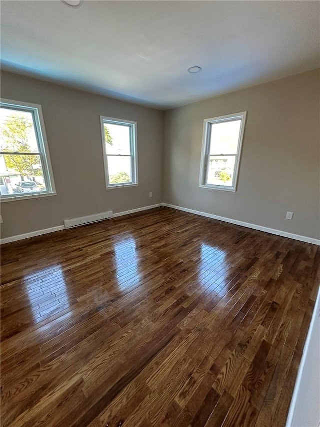 spare room featuring plenty of natural light, dark hardwood / wood-style flooring, and a baseboard heating unit