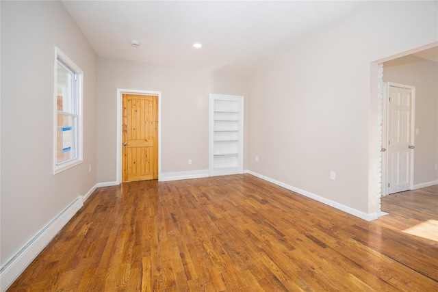 empty room with a baseboard heating unit and hardwood / wood-style flooring