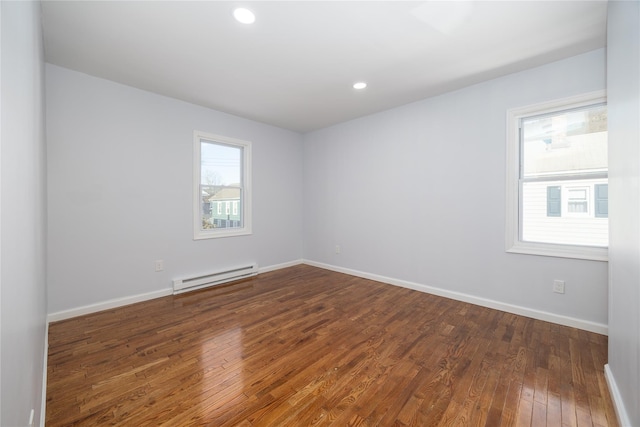 spare room with dark hardwood / wood-style flooring and a baseboard heating unit