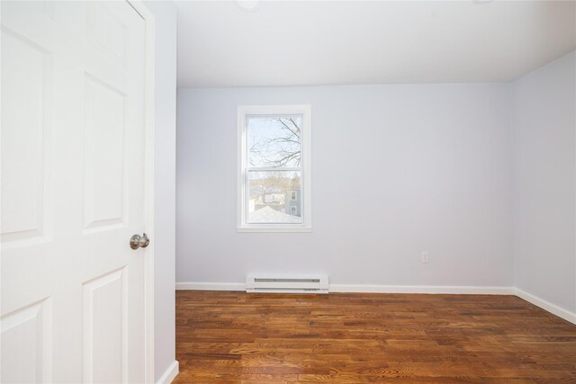 empty room featuring baseboard heating and dark hardwood / wood-style floors