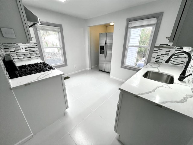 kitchen featuring gray cabinetry, decorative backsplash, stainless steel fridge, and sink