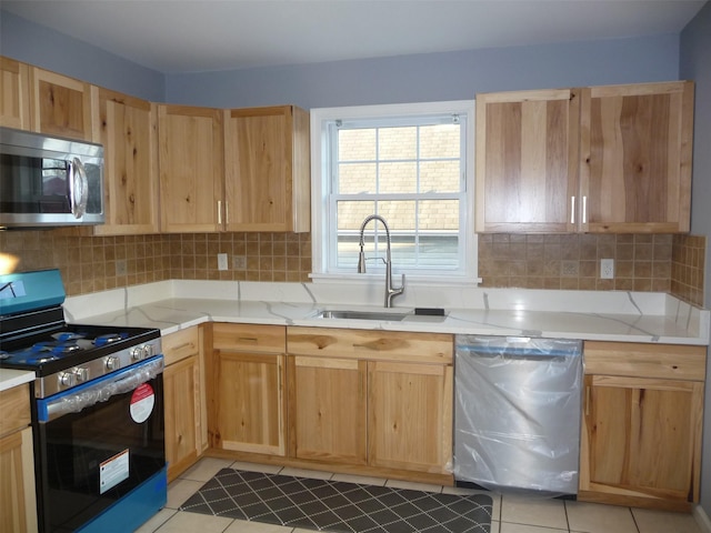 kitchen featuring sink, light tile patterned floors, appliances with stainless steel finishes, tasteful backsplash, and light stone counters