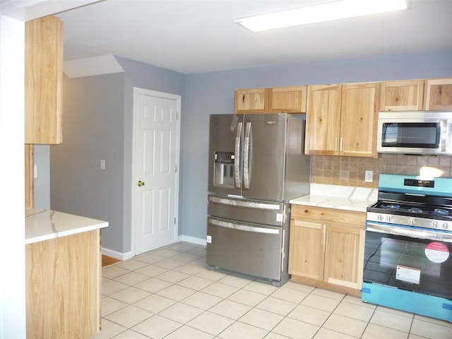 kitchen with light brown cabinets, light tile patterned floors, backsplash, and appliances with stainless steel finishes