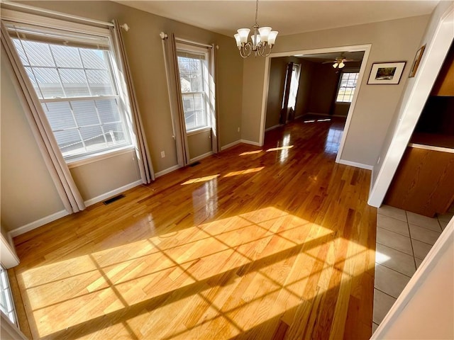 unfurnished dining area with hardwood / wood-style floors, an inviting chandelier, and a healthy amount of sunlight