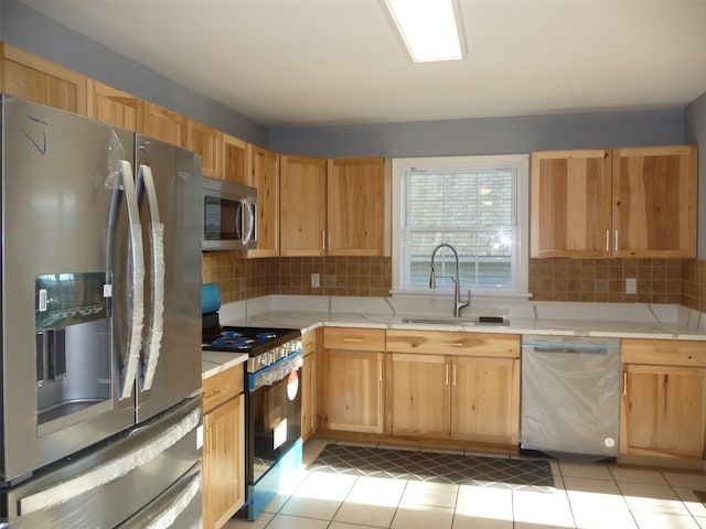 kitchen with sink, light brown cabinets, backsplash, light tile patterned floors, and appliances with stainless steel finishes