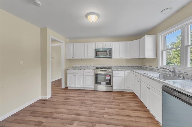 kitchen featuring white cabinetry, sink, appliances with stainless steel finishes, and light hardwood / wood-style flooring