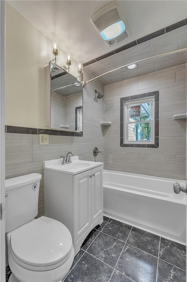 full bathroom featuring vanity, toilet, tile walls, and tiled shower / bath combo