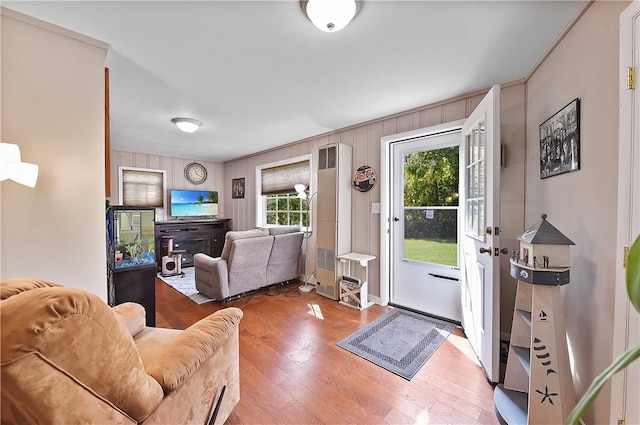 living room featuring hardwood / wood-style flooring, ornamental molding, and wood walls