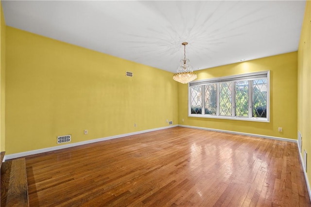 empty room with an inviting chandelier and hardwood / wood-style flooring