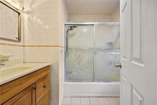 bathroom with tile patterned floors, vanity, bath / shower combo with glass door, and tile walls