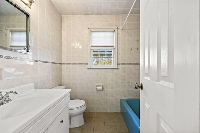 bathroom with toilet, vanity, tile patterned floors, and tile walls