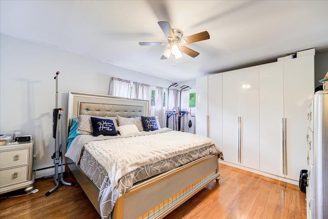 bedroom featuring a baseboard heating unit, ceiling fan, and light wood-type flooring