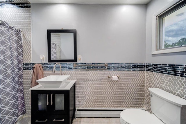 bathroom featuring tile walls, vanity, toilet, and baseboard heating