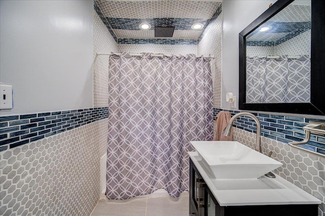 bathroom featuring tile patterned floors, vanity, curtained shower, and tile walls