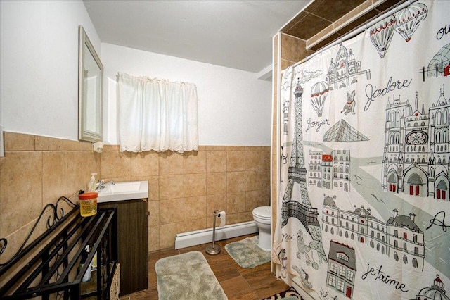 bathroom with toilet, tile walls, baseboard heating, vanity, and hardwood / wood-style flooring