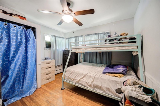 bedroom featuring a baseboard radiator, light hardwood / wood-style floors, and ceiling fan